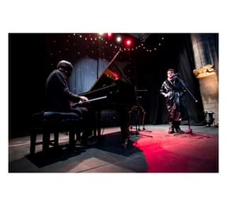 Image may contain: 1 person, dancing, playing a musical instrument, on stage, night and indoor