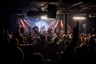 Image may contain: one or more people, people dancing, people playing musical instruments, people on stage, night, concert, crowd and indoor