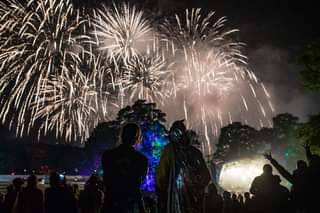 Image may contain: one or more people, people standing, people on stage, fireworks, night, sky and outdoor