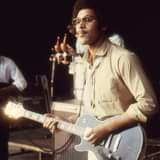 Image may contain: 1 person, playing a musical instrument, on stage, night, guitar and close-up