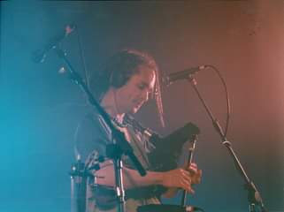 May be an image of 1 person, standing, playing a musical instrument and guitar
