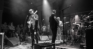 May be a black-and-white image of 1 person, standing, playing a musical instrument, guitar and indoor