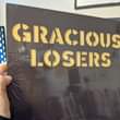 May be an image of text that says "GRACIOUS LOSERS"