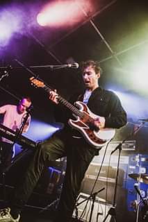 May be an image of 2 people, people playing musical instruments, people standing, guitar and indoor